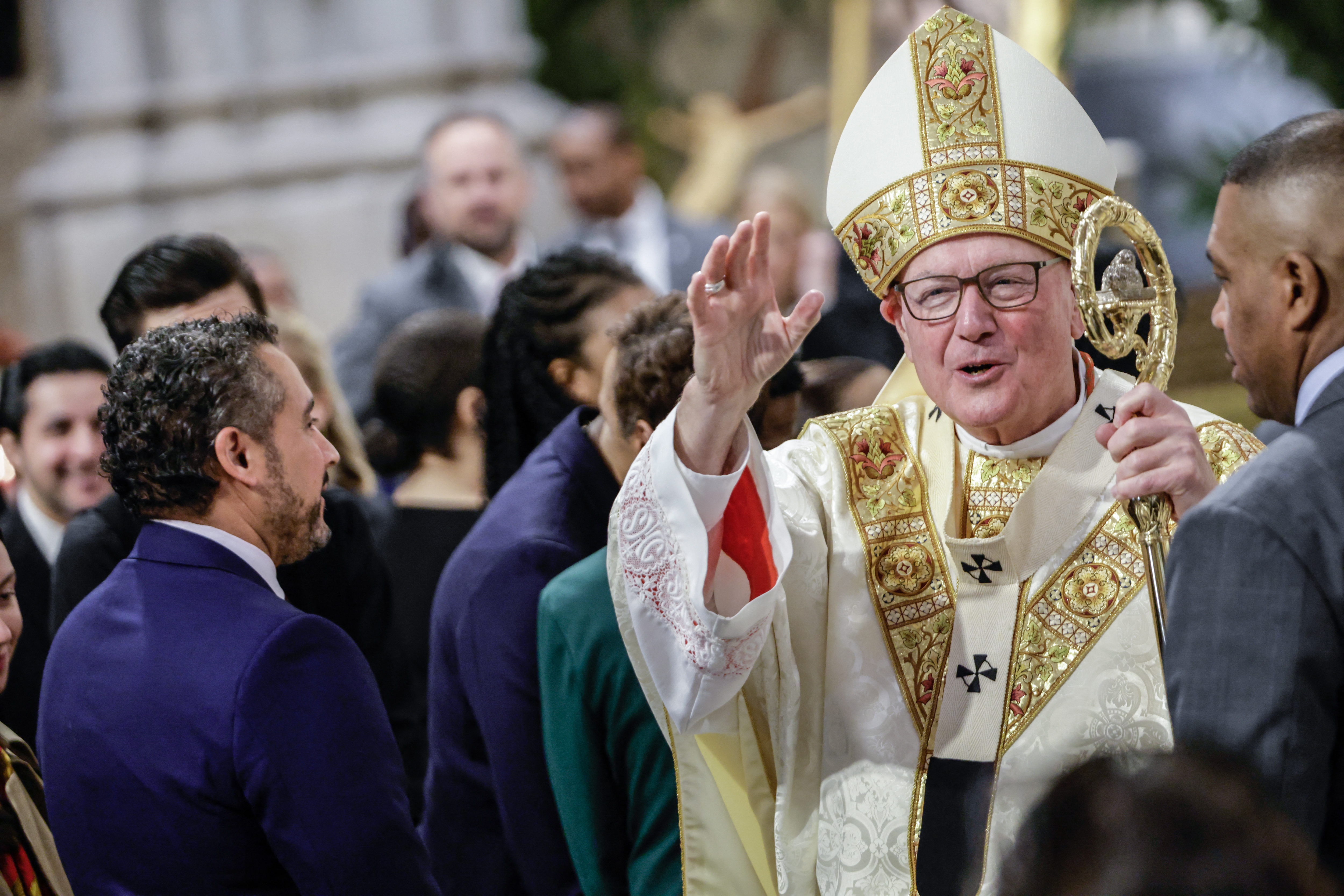 A religious leader in ornate ceremonial attire greets a group of people, engaging in conversation at a formal event