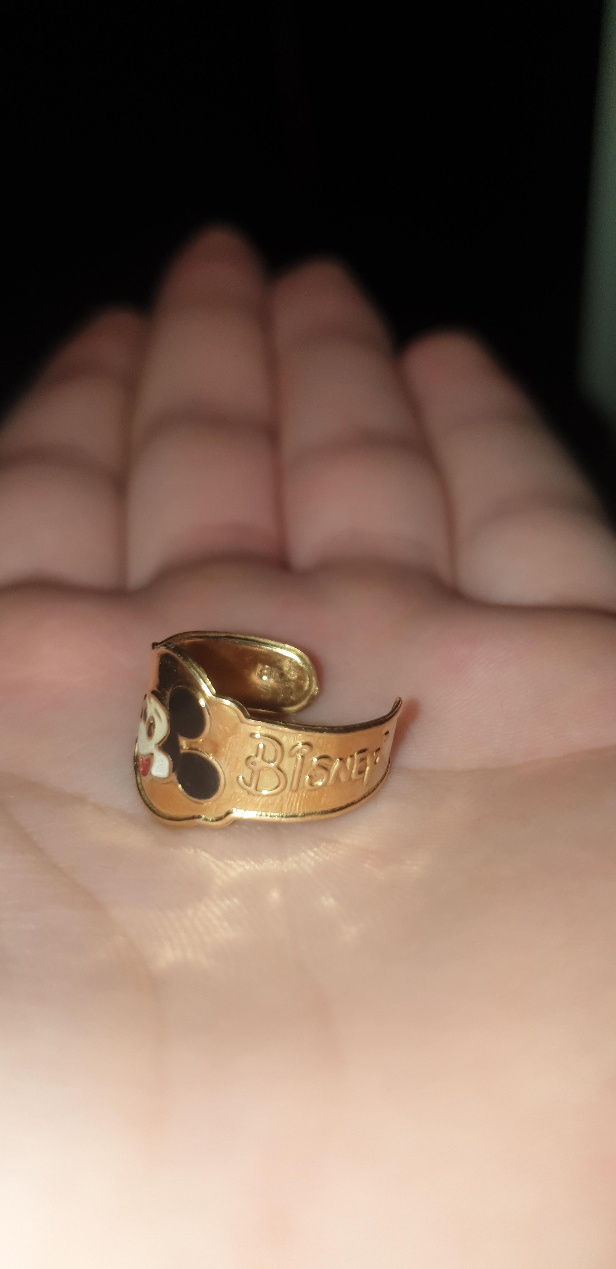 An open palm holds a Disney-themed ring, featuring a Mickey Mouse design on the band