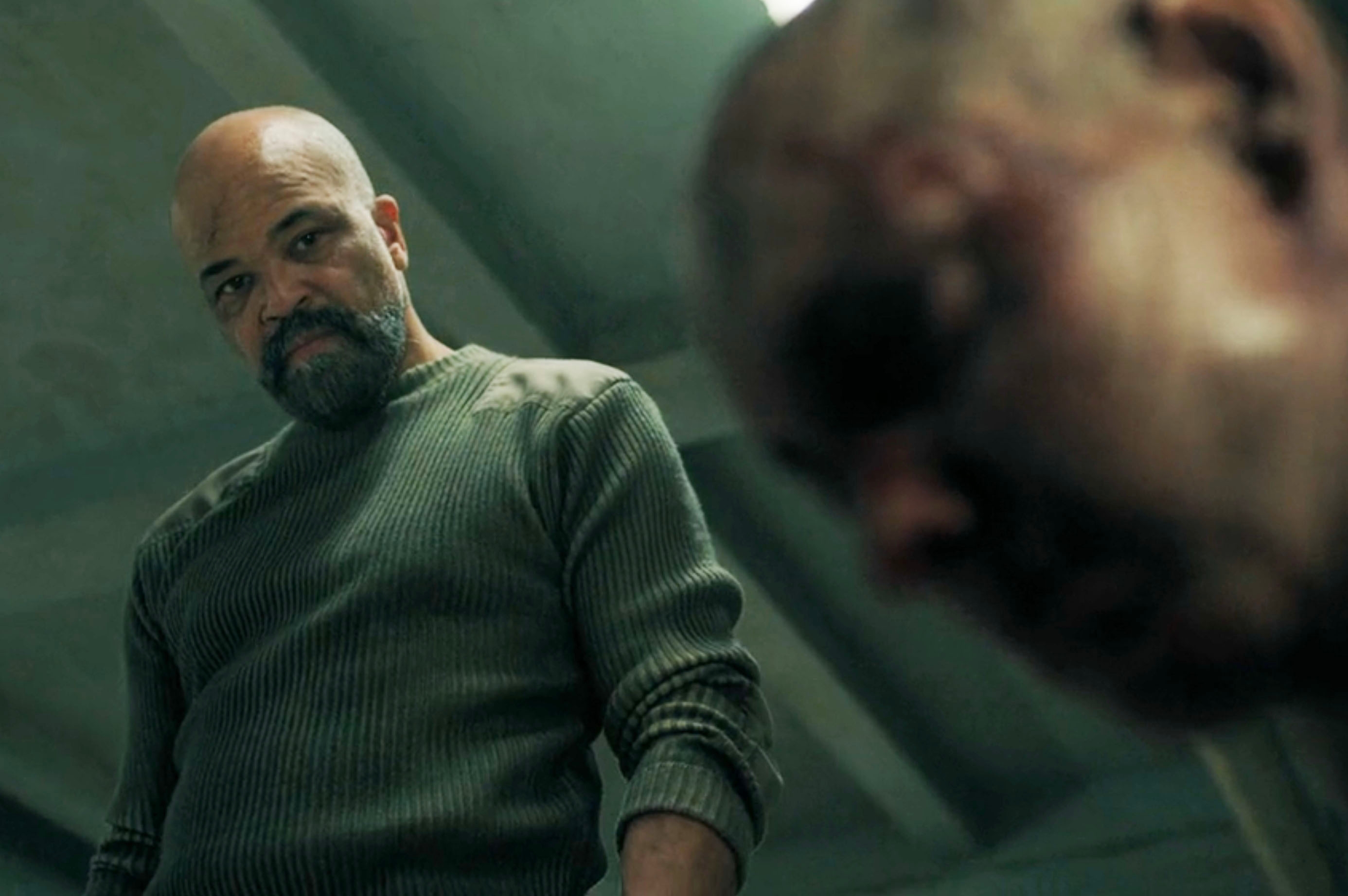 Jeffrey Wright as Isaac looking menacingly at a beaten and bloody person