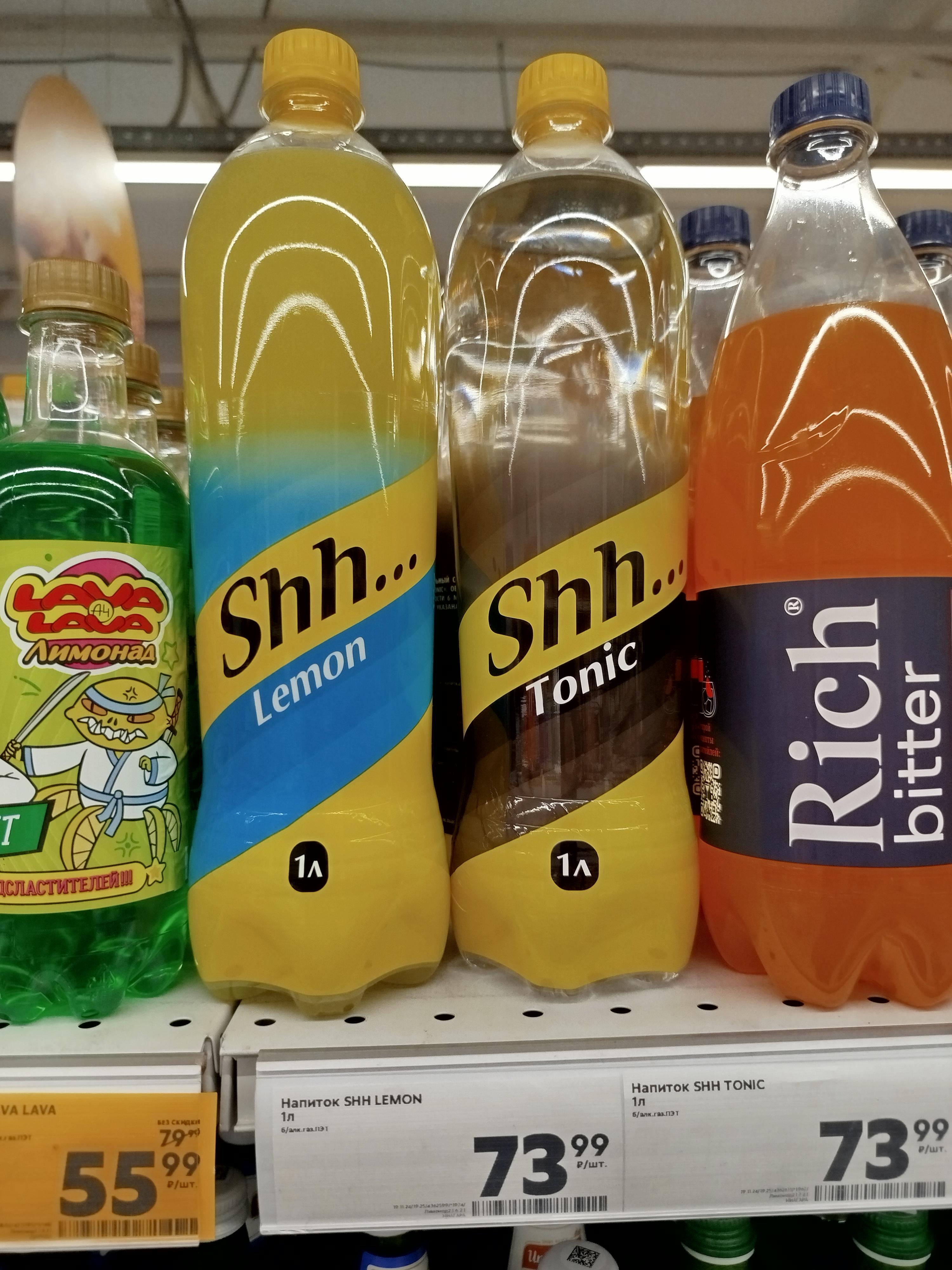 Lemon and tonic bottles labeled "Shh…" and a bitter drink labeled "Rich" are displayed on a supermarket shelf