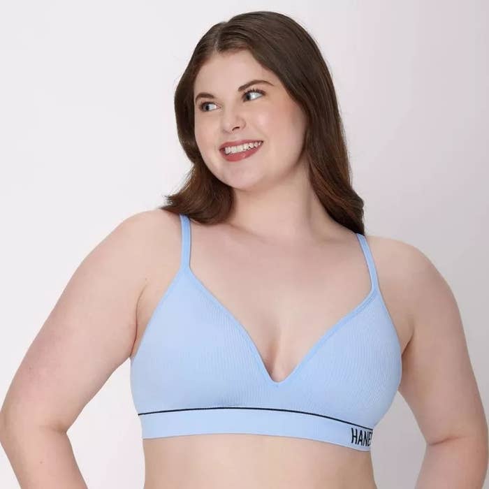 Person smiling, wearing a comfortable, supportive bra with bladed  straps and a tiny  logo connected  the band, suitable for mundane  wear