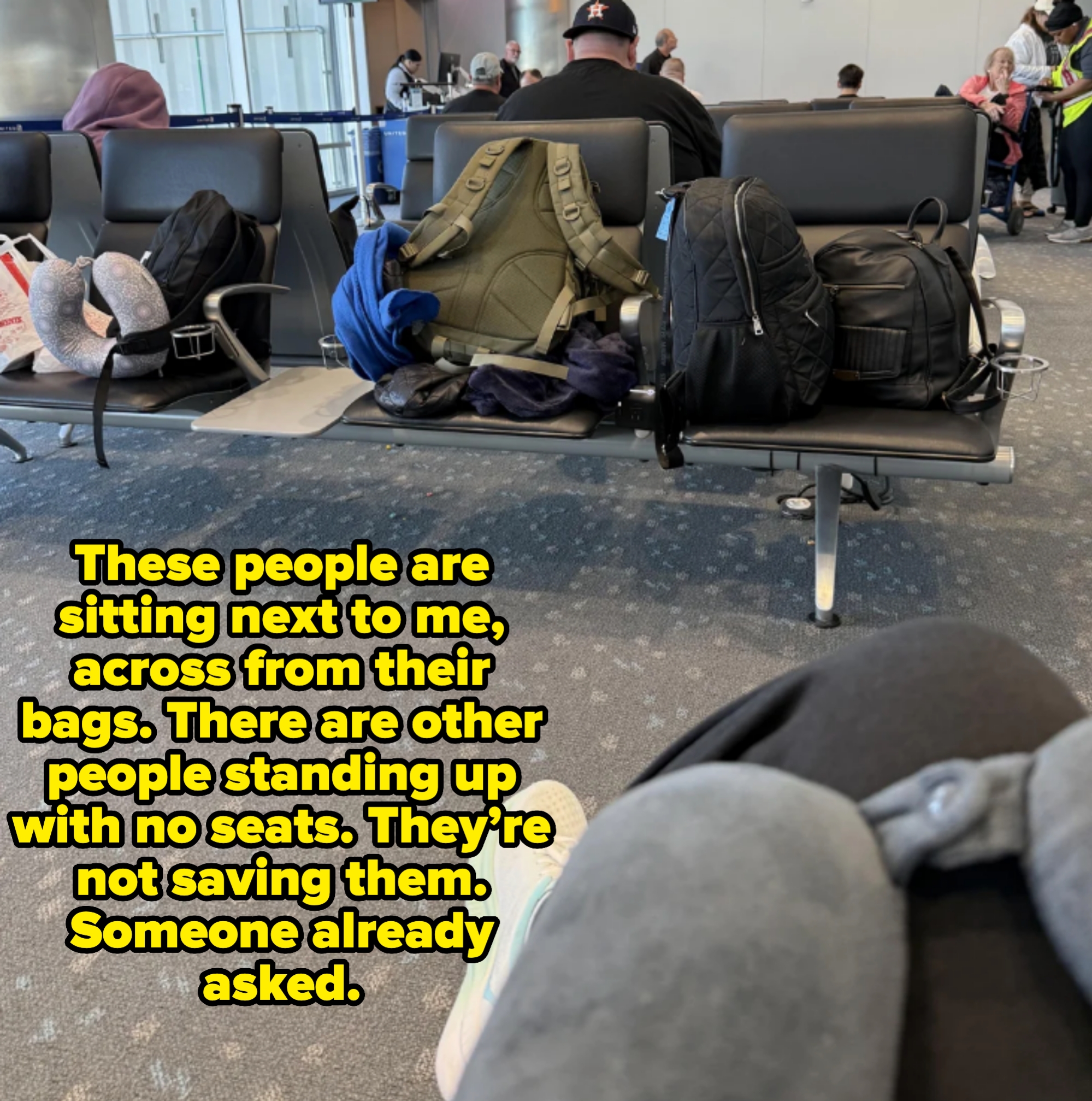 Airport seating area with luggage on chairs, captioned &quot;These people are sitting next to me, across from their bags. There are other people standing up with no seats. They’re not saving them. Someone already asked&quot;