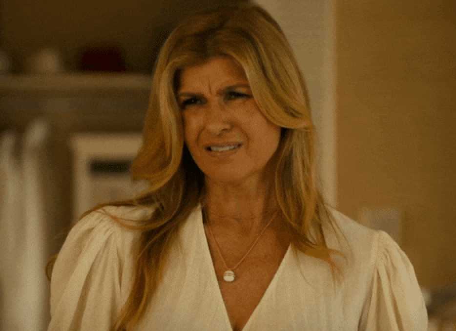 Woman with long hair in a white blouse making a displeased expression indoors