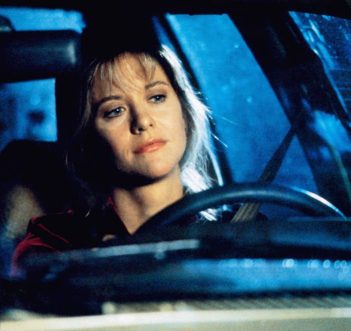 Person sitting in a car, looking thoughtful, with hands on the steering wheel at night