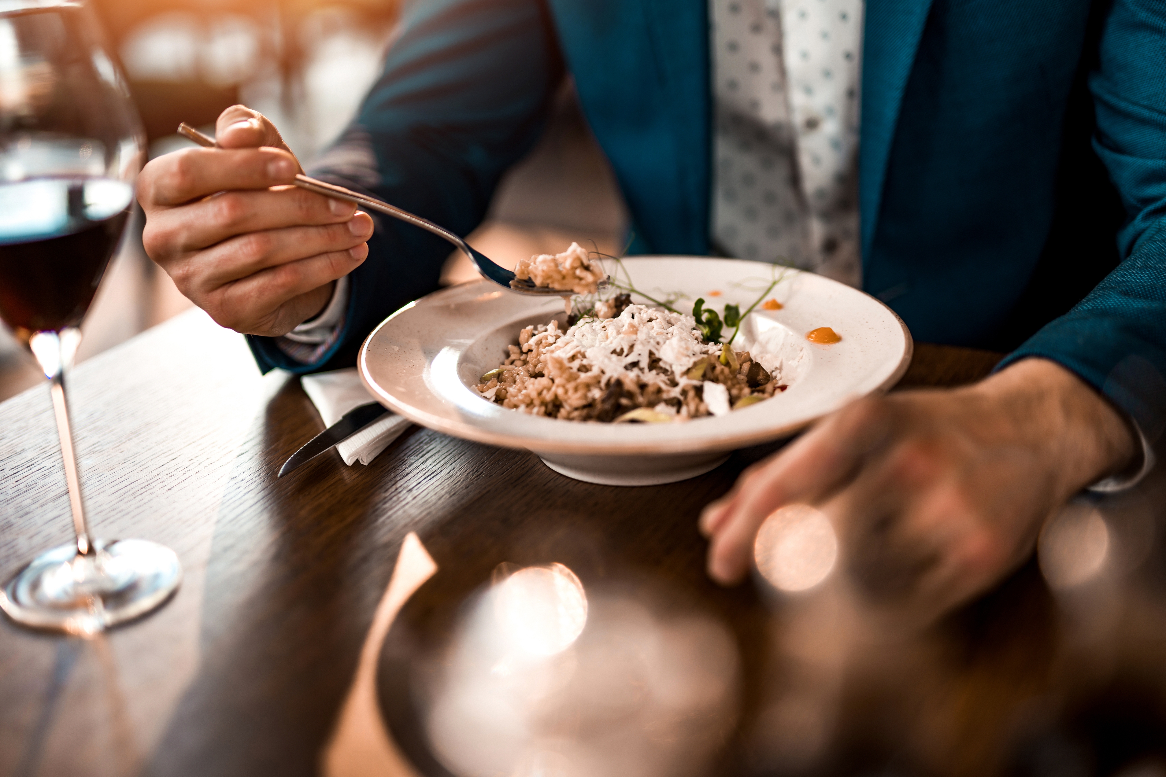 Person in formal attire eating a gourmet dish at a restaurant table
