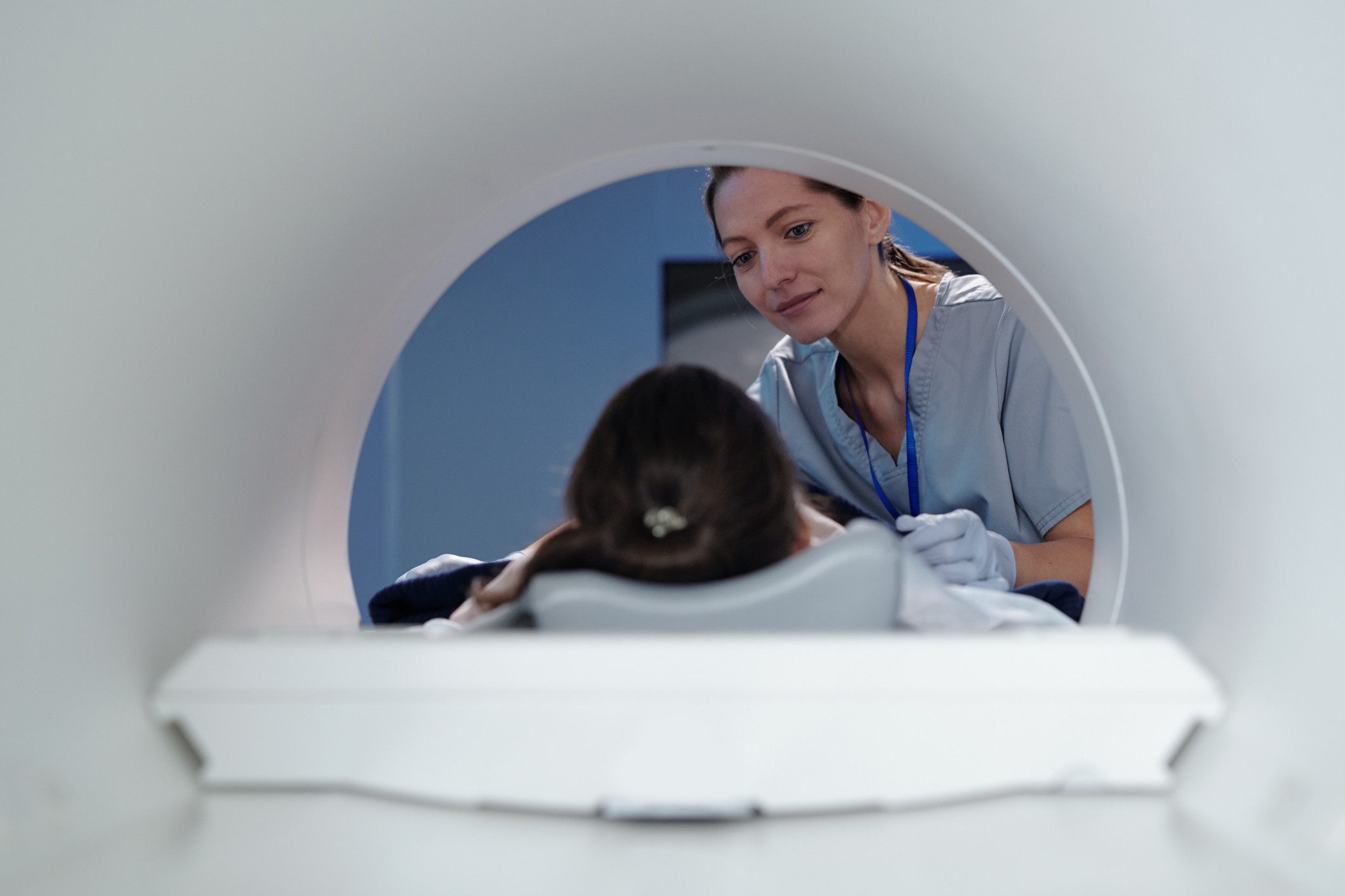 A medical professional checks on a patient lying inside an MRI scanner, focusing on patient care and comfort