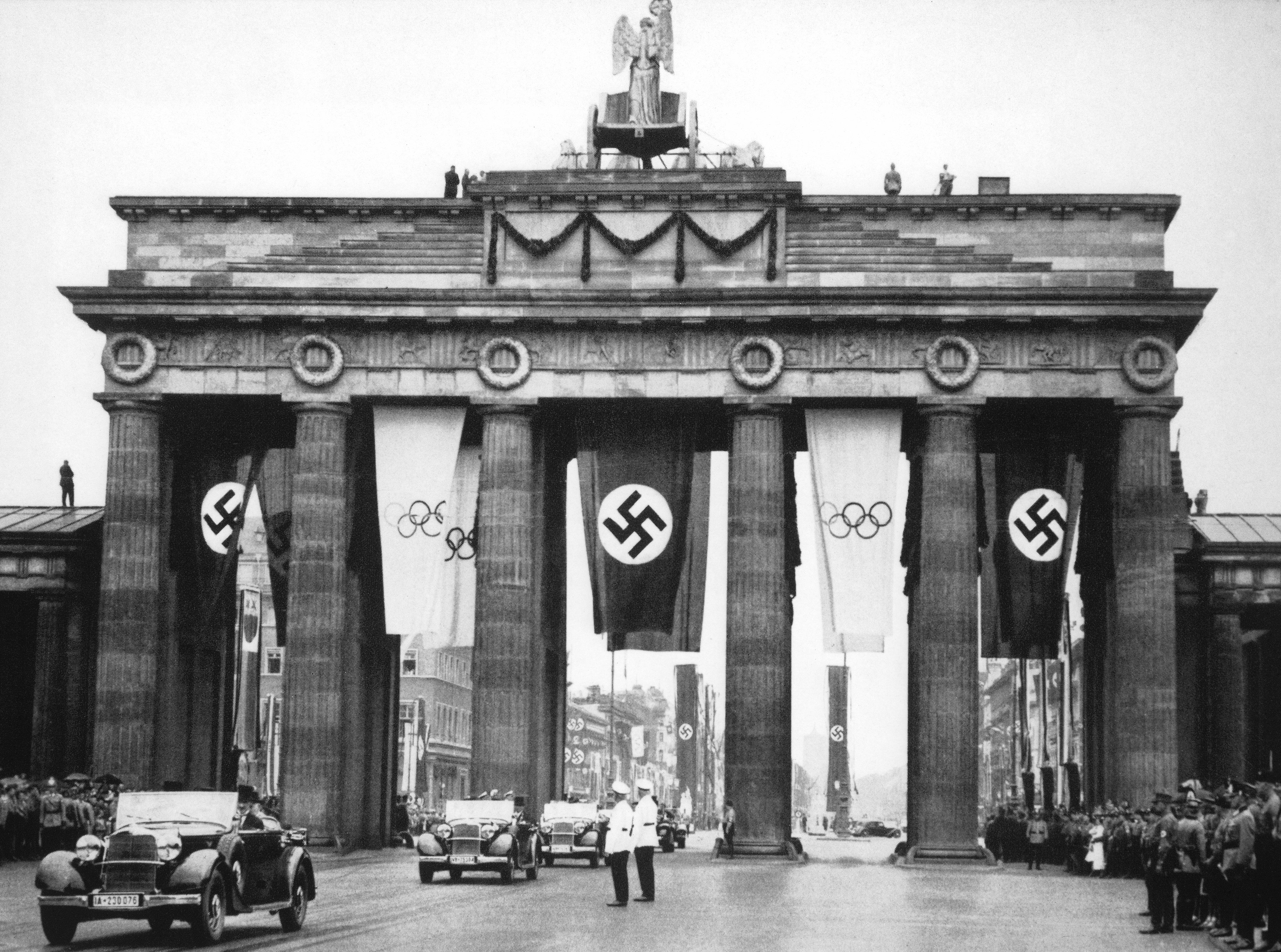 Historic image of the Brandenburg Gate in Berlin, decorated with swastika and Olympic flags, during the 1936 Summer Olympics