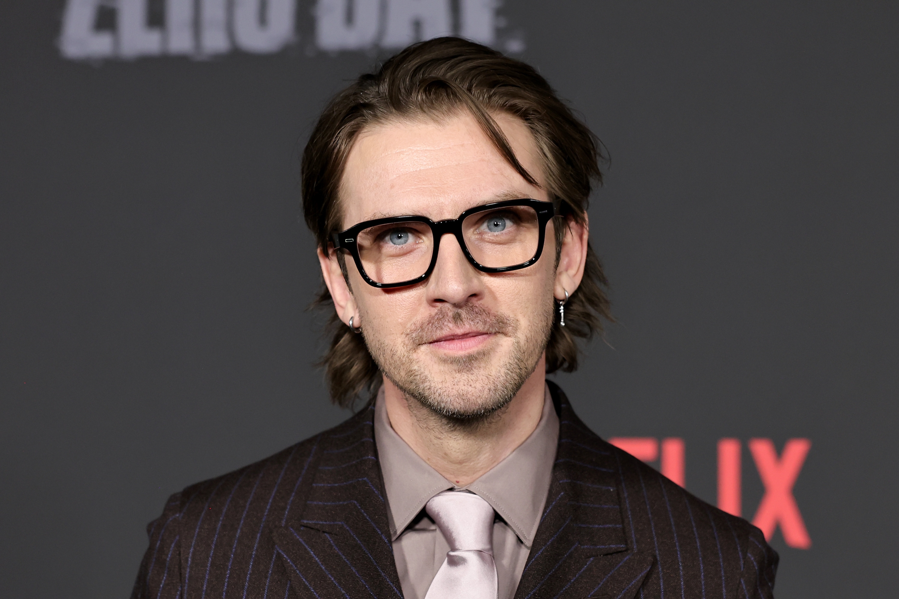 Person in a pinstripe suit with glasses at a TV event