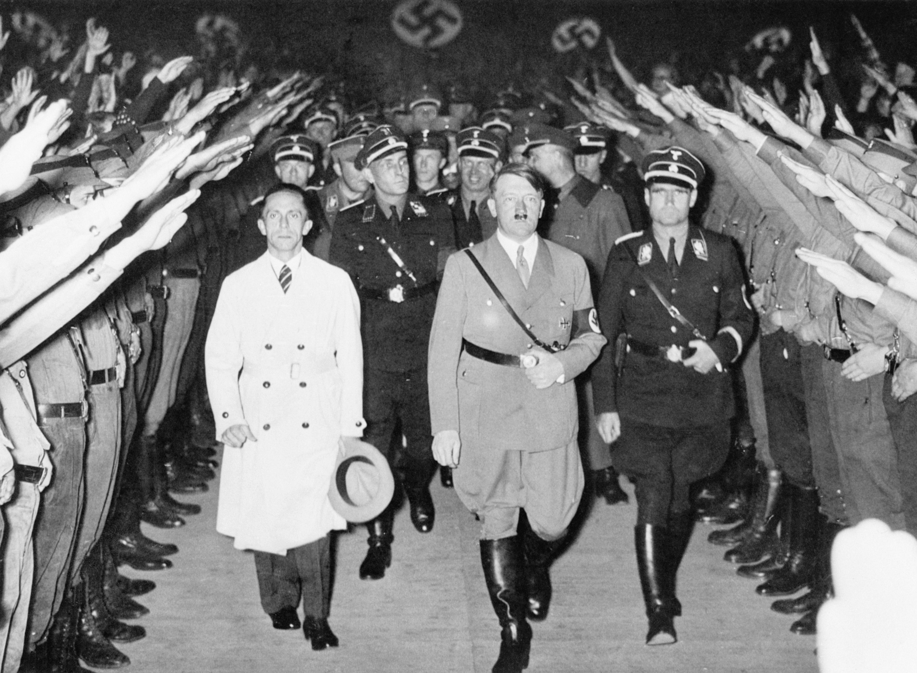 A historical photo shows Hitler walking among a uniformed crowd giving a raised-arm salute