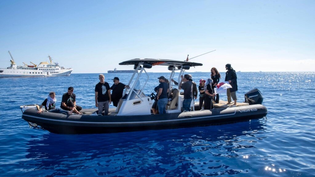 People on a motorboat in the ocean, with a large ship visible in the background