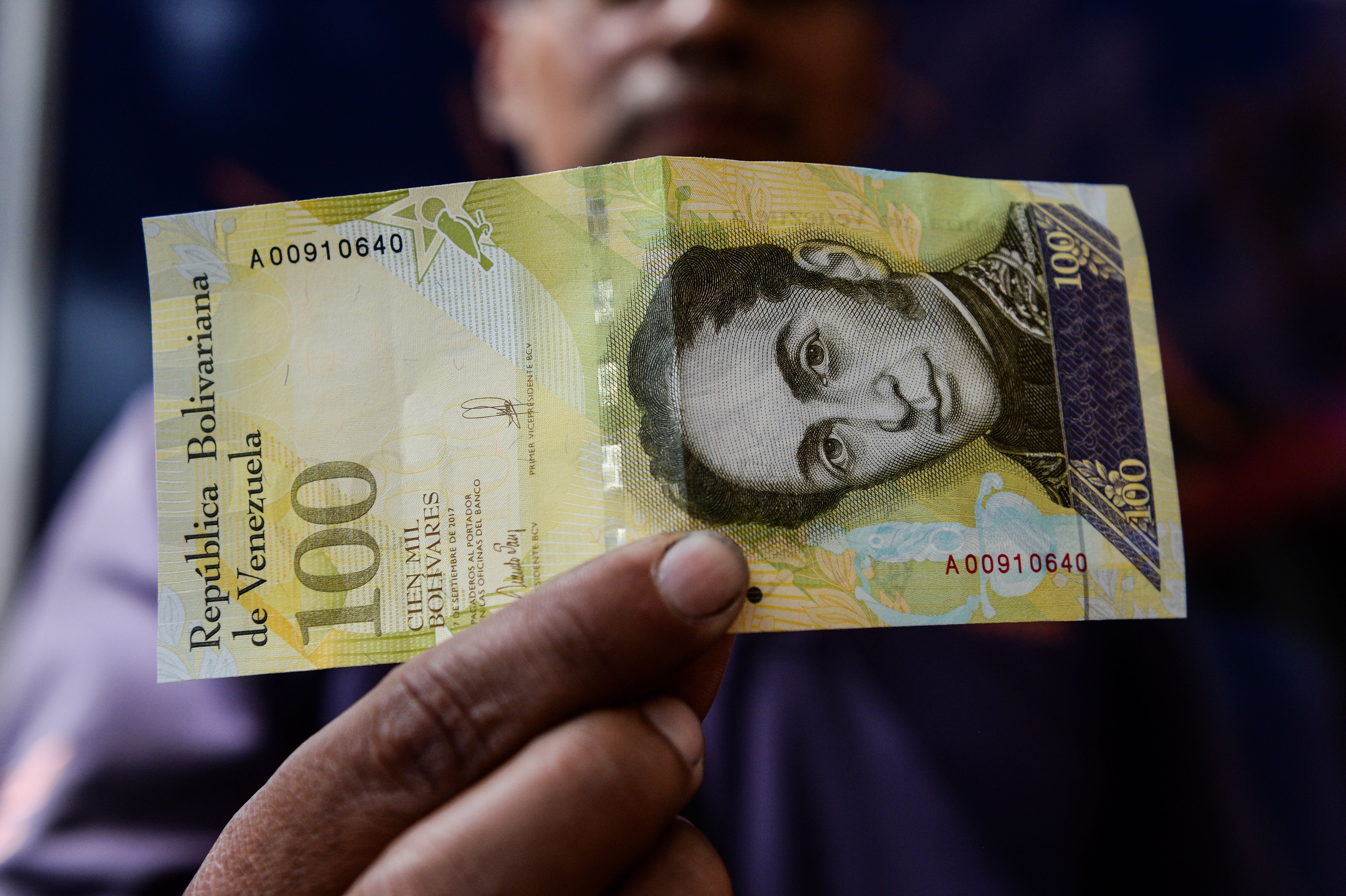 Person holding a 100 Venezuelan bolívar banknote with Simón Bolívar's portrait visible