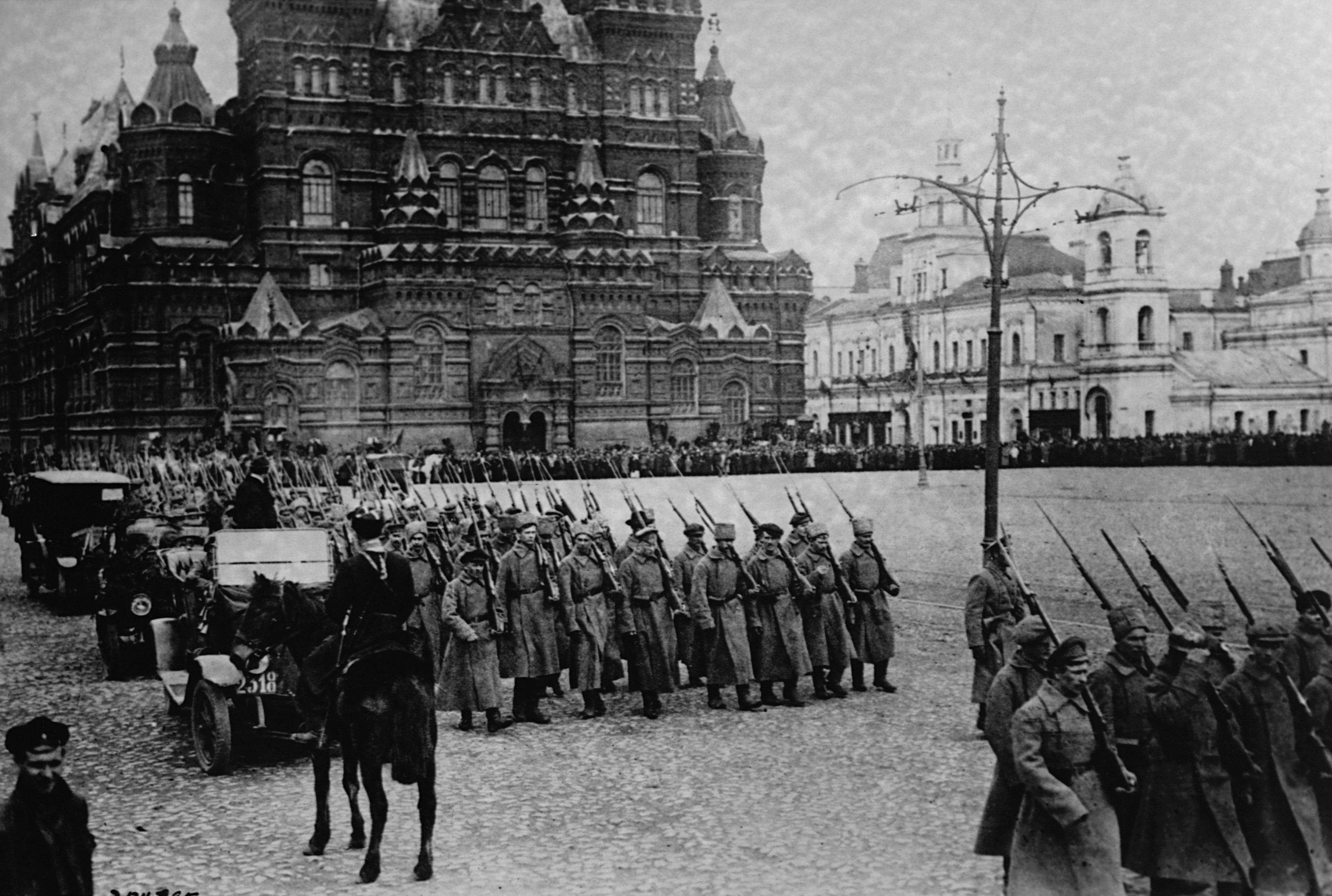 Historic photo of soldiers marching in formation in front of an ornate building, possibly a historic event or military parade