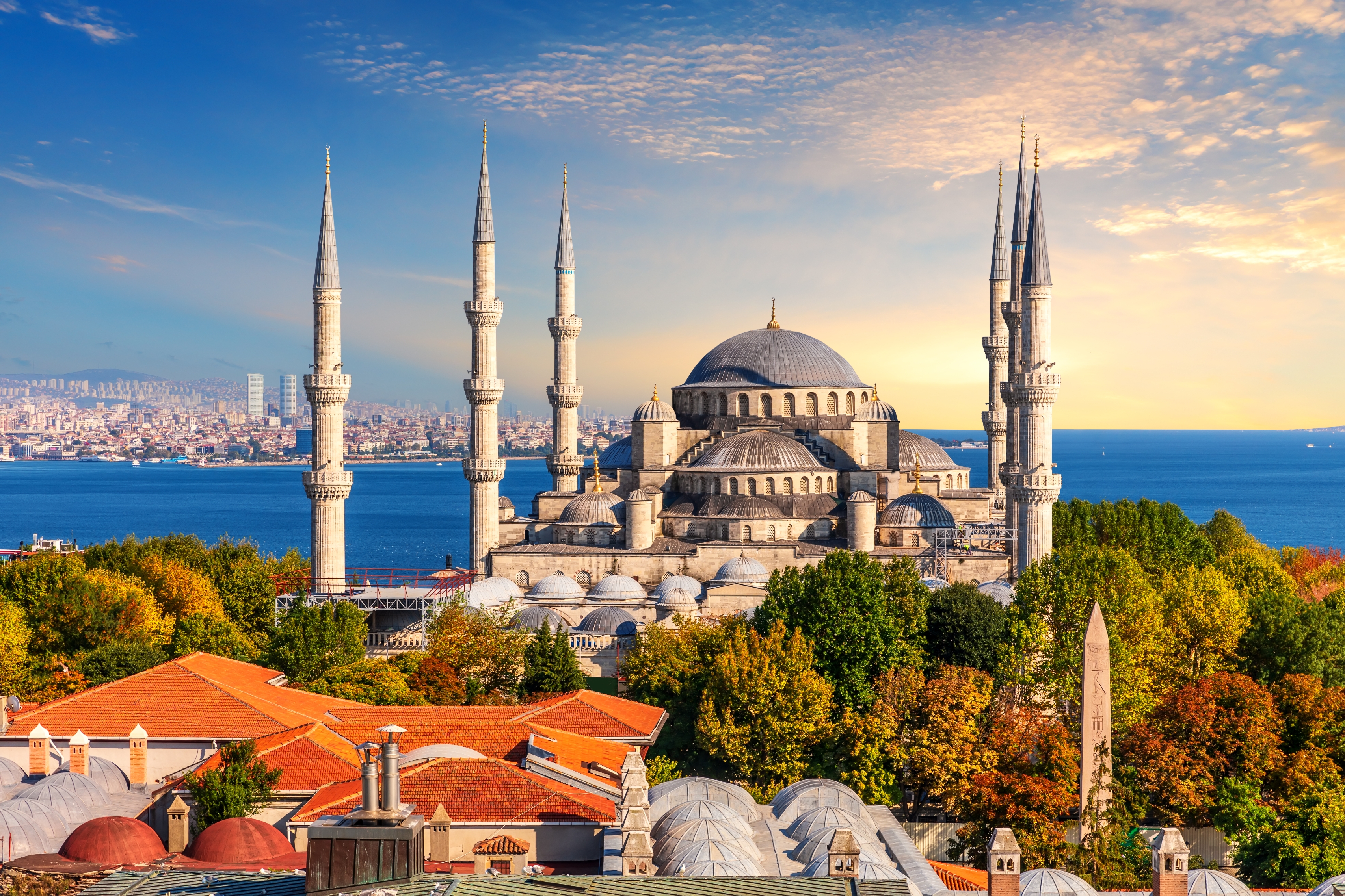 View of the Blue Mosque in Istanbul with its six minarets, surrounded by lush trees and overlooking the Bosphorus Strait