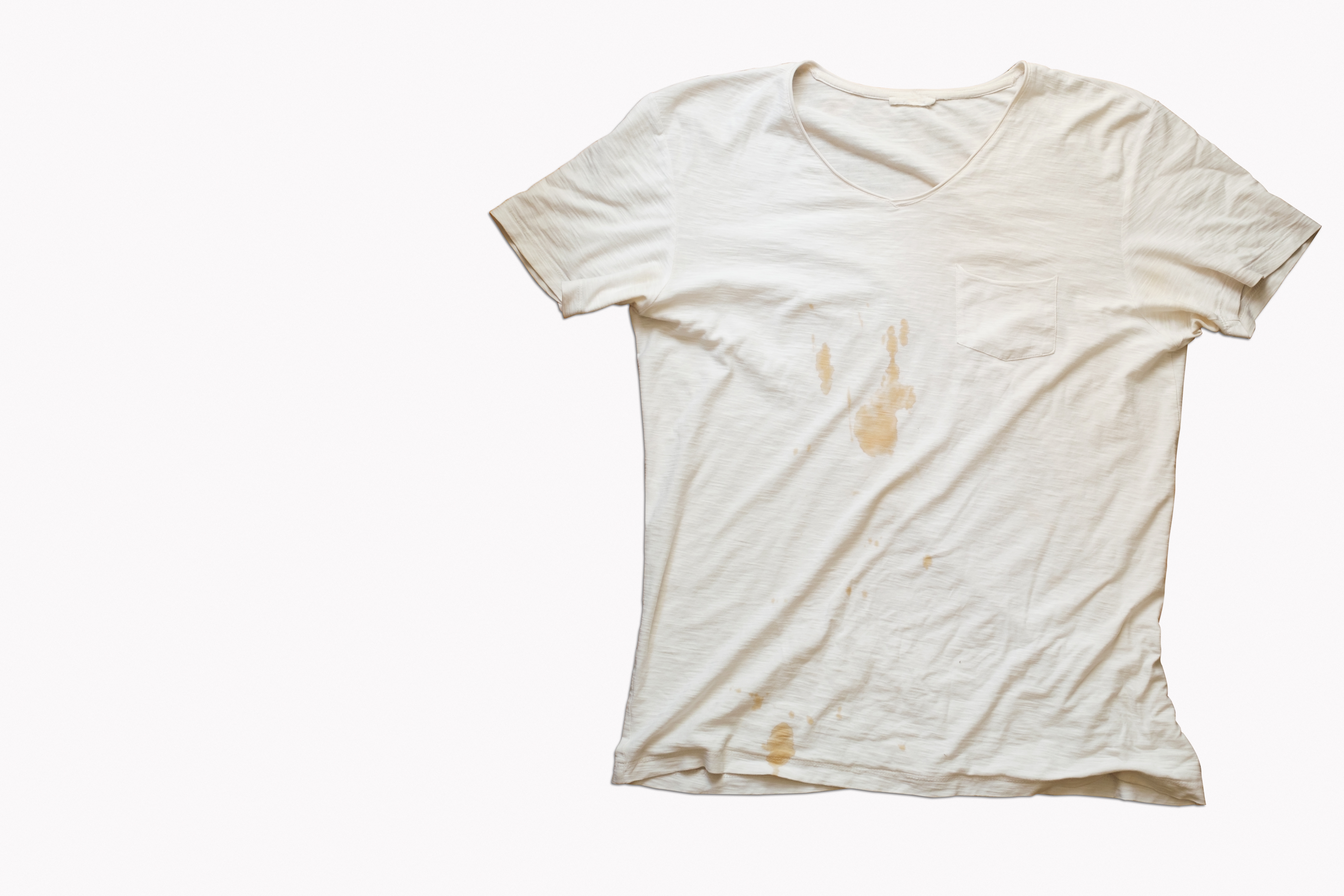 A worn white T-shirt with visible stains on the front, laid flat on a plain surface