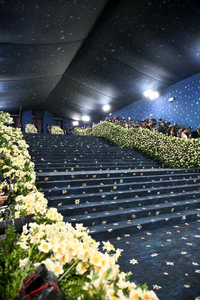 Lavish staircase decorated with white flowers, lined with photographers and guests