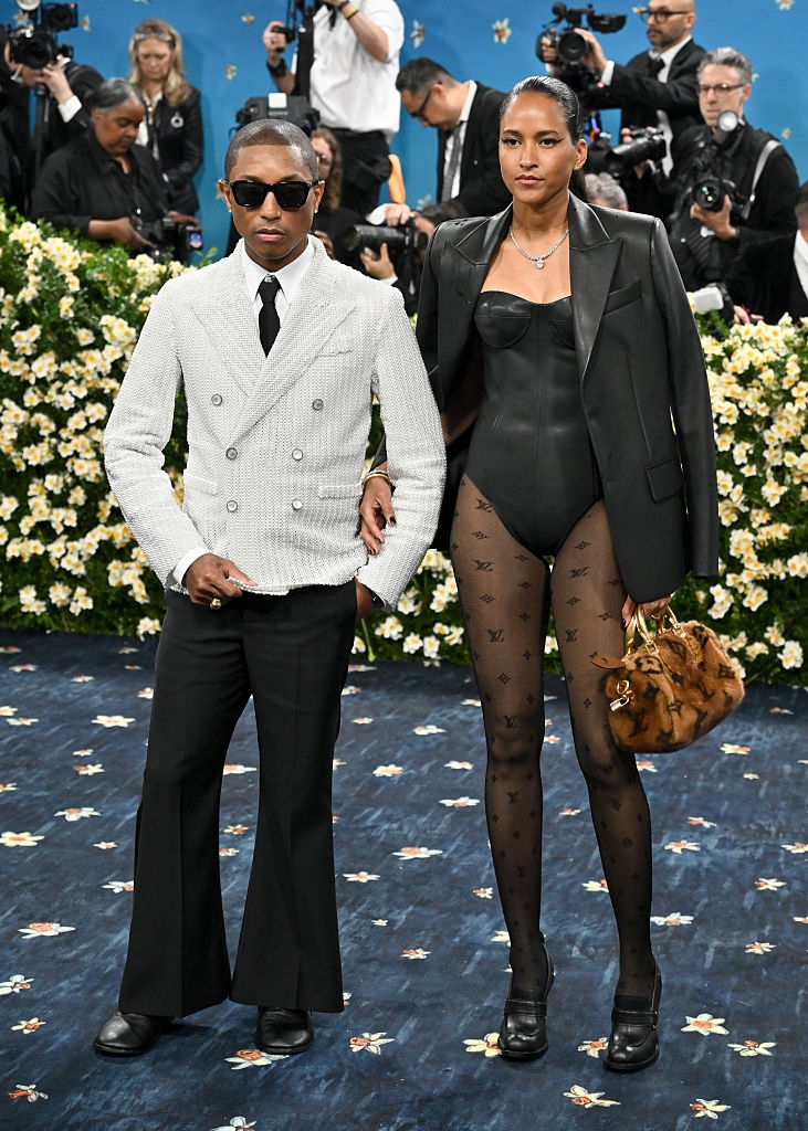 Pharrell in a tailored pinstripe suit and dark wide-legged pants, and Helen in a leather bodysuit with an oversized blazer