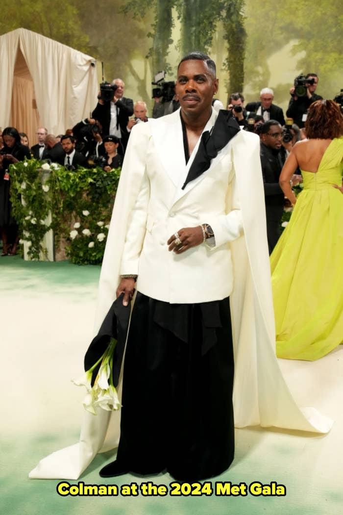 Colman in a jacket with cape, holding calla lillies, labeled as his 2024 Met Gala look