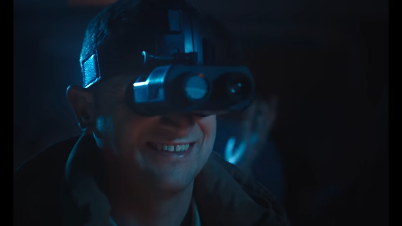 Person with night vision goggles smiling in a dark environment