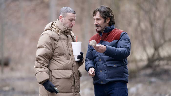 Two radical outdoors, 1 holding a drink, some successful wintertime coats. They are engaged successful conversation, 1 showing thing to the other