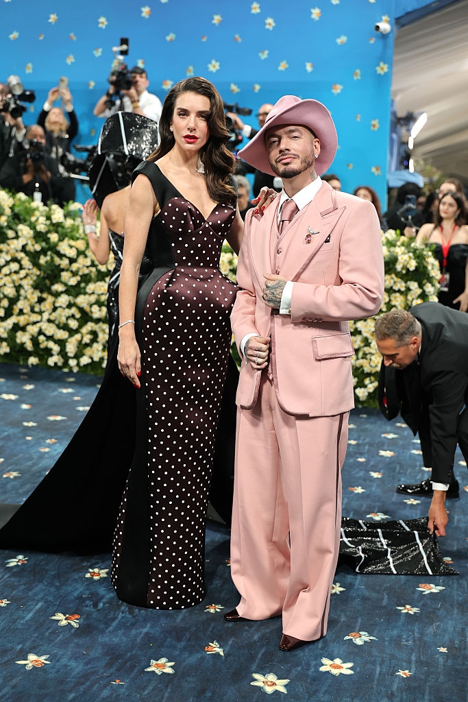 Valentina wears a sophisticated polka dot dress; J Balvin wears a stylish suit and hat