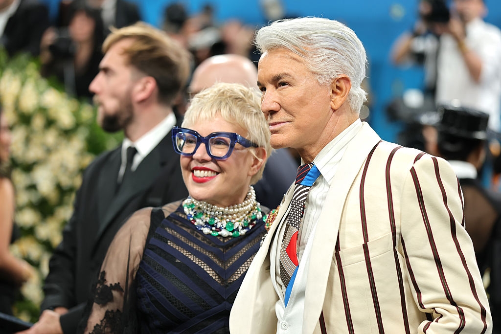 Close up of the couple, she has bold glasses and a statement necklace, and he has a patterned tie