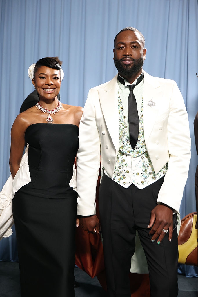 she wears a silver necklace, and he wears a detailed waistcoat