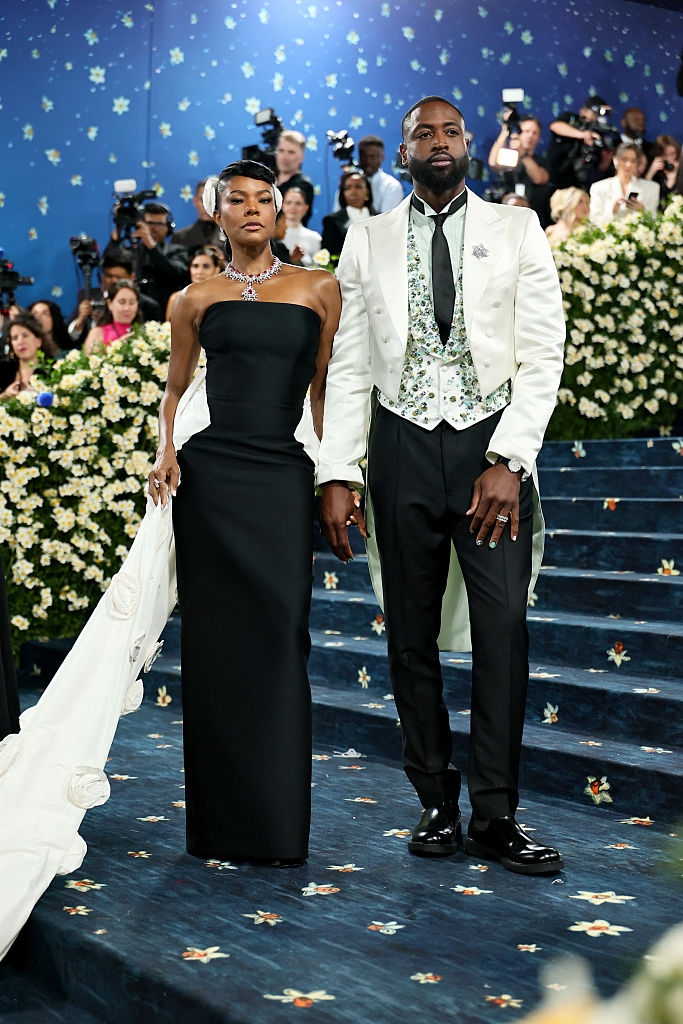 Dwayne in a tuxedo with floral details and Gabrielle in a strapless gown with a cape
