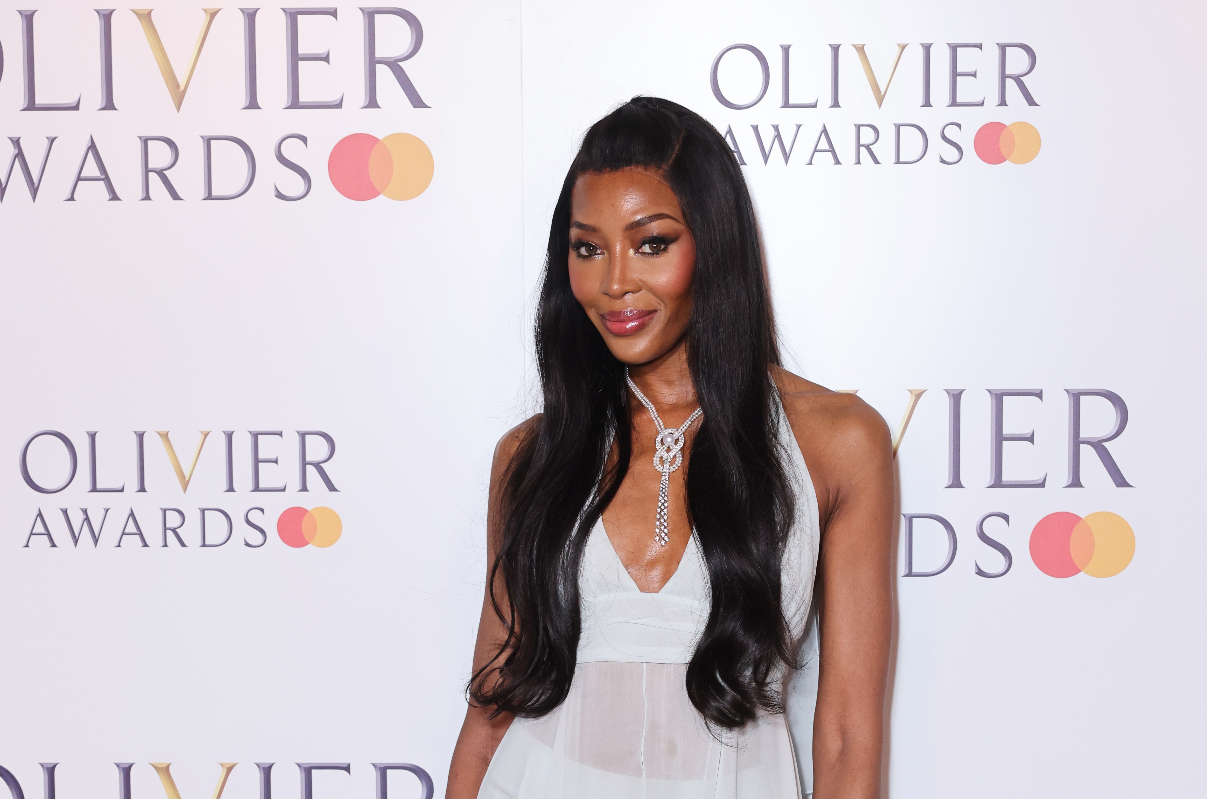 Naomi Campbell in elegant sleeveless gown at Olivier Awards, featuring a diamond necklace and long, flowing hair