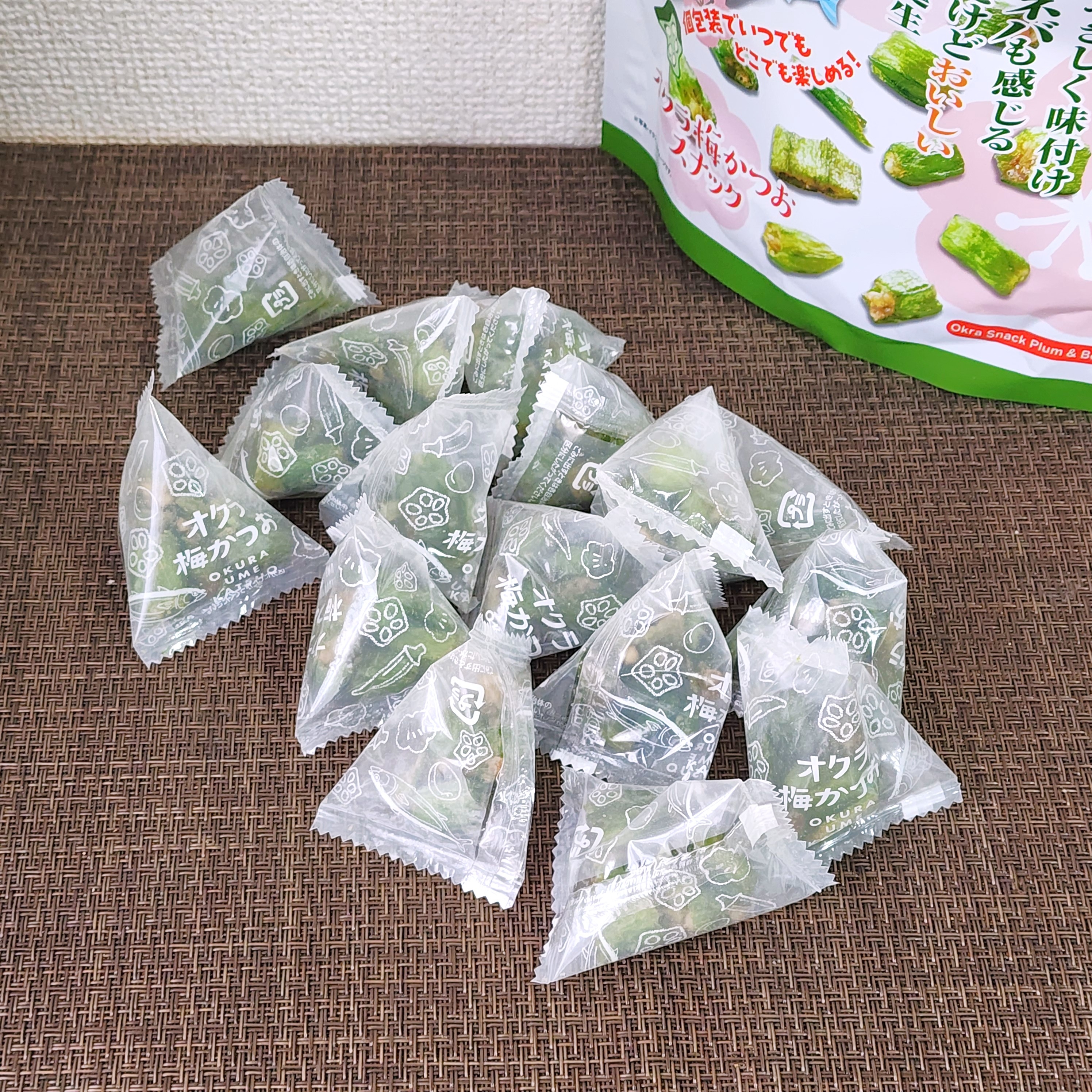 卓上に緑茶風味のキャンディが数個並ぶ。背景に製品のパッケージも見える。