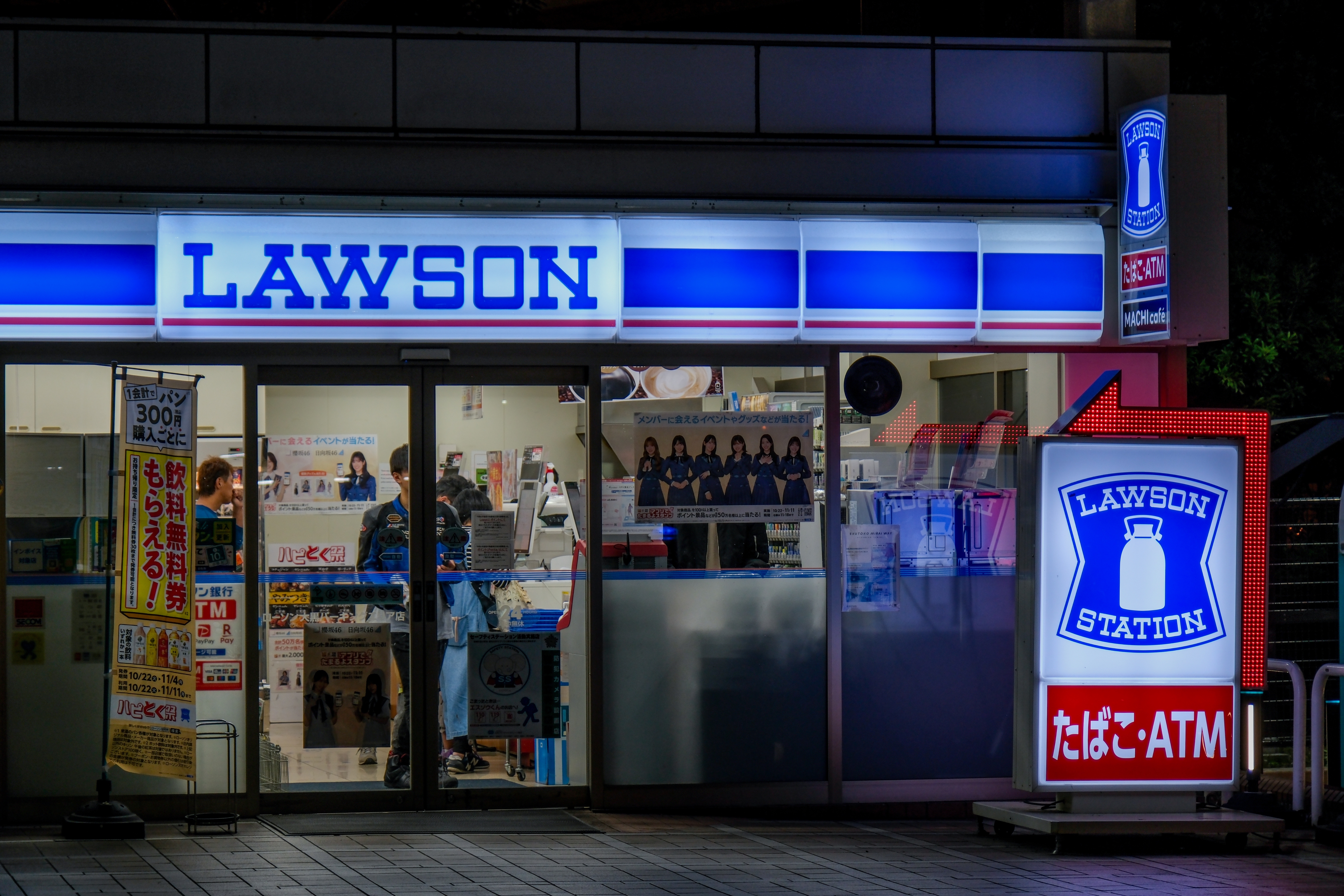 Exterior of a Lawson convenience store at night, with bright signage and window displays