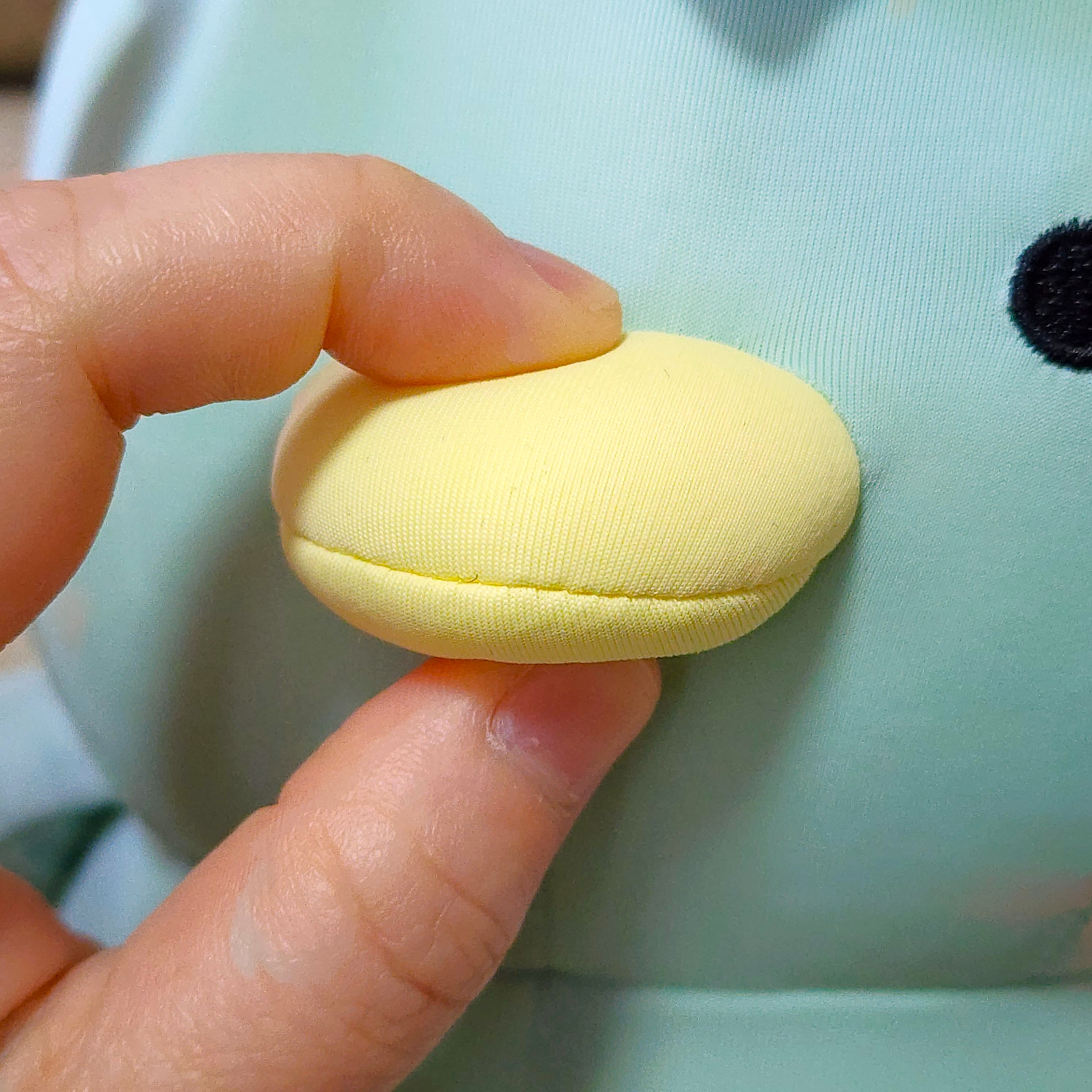 ぬいぐるみの目の近くの丸いパーツを指でつまんでいる様子。