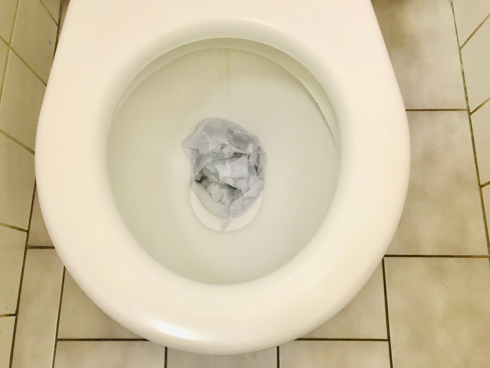 Toilet with crumpled paper inside the bowl, suggesting improper disposal of toilet paper
