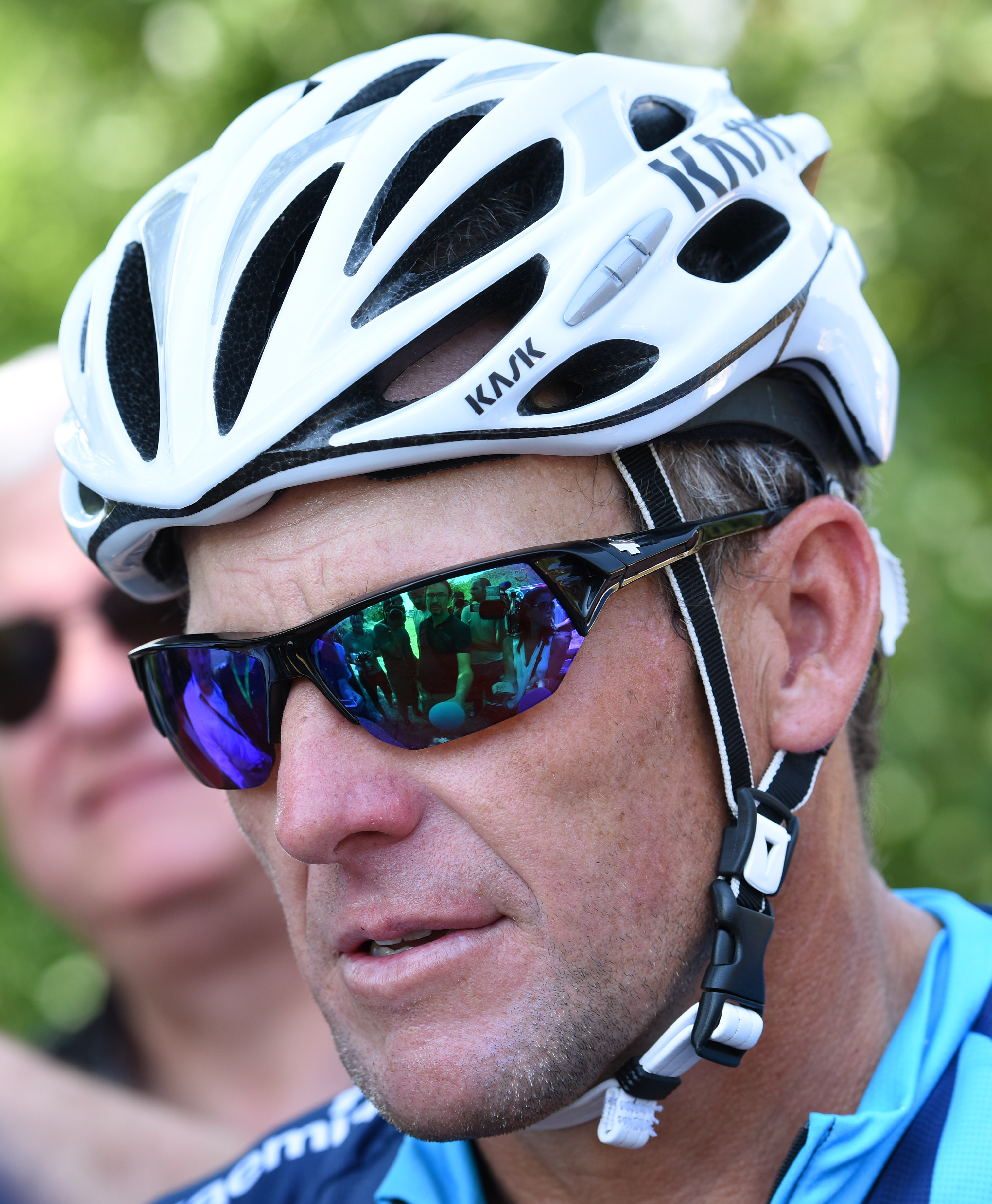 Person wearing a cycling helmet and sunglasses, dressed in sportswear, focused and outdoors