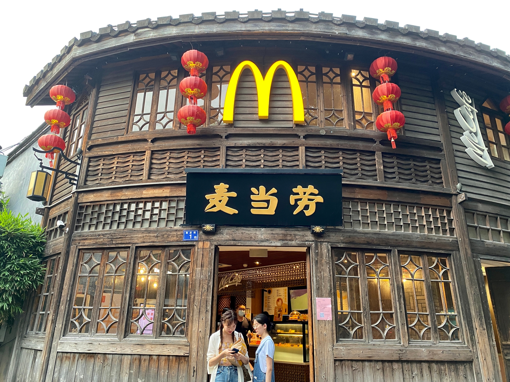Traditional-style McDonald's building with red lanterns. Two people are standing outside, looking at a phone
