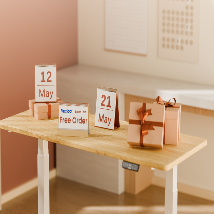 Desk with calendar showing May 12 and 21, gift boxes, and a sign reading "Flexispot Brand Sale Free Order."