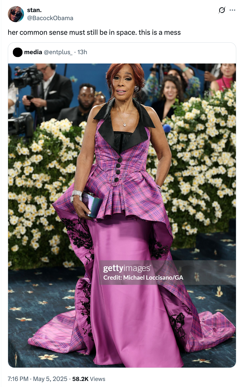 Woman in a plaid gown with layered design, holding a clutch, poses at a formal event, surrounded by flowers