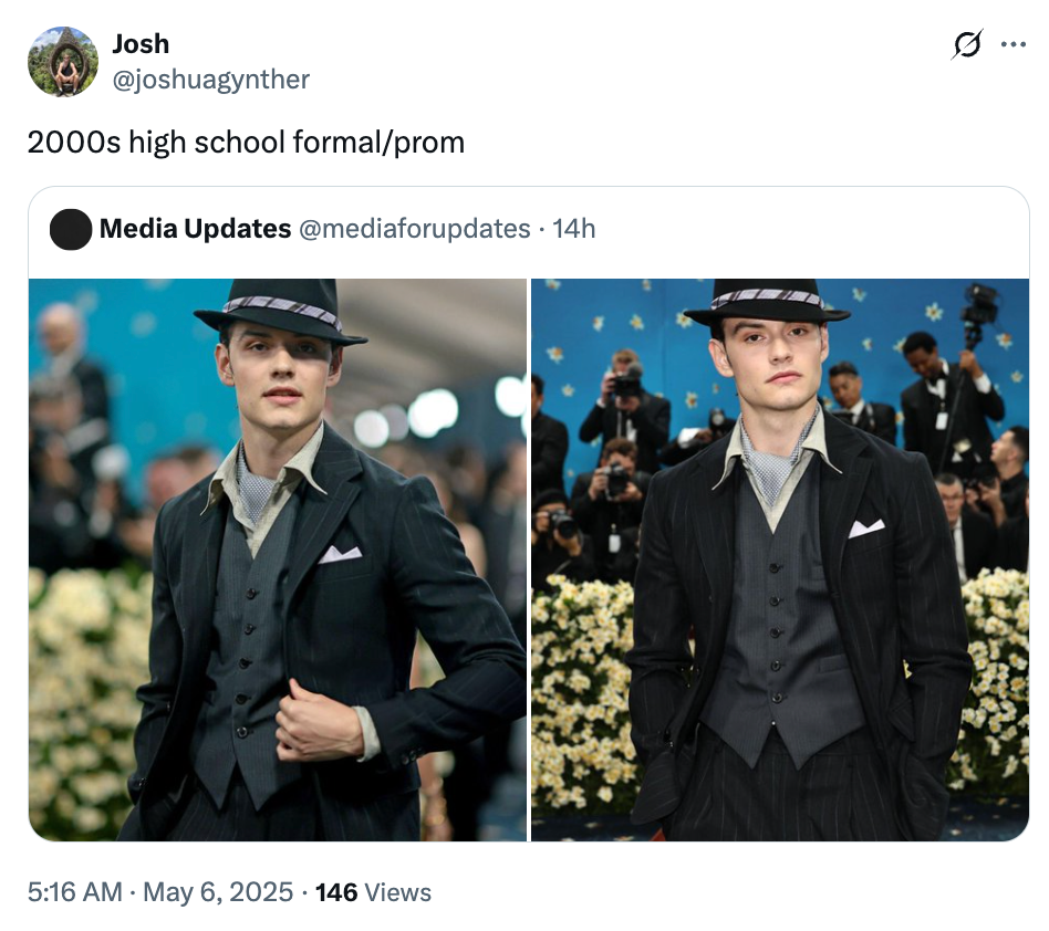 Person in vintage 1920s-style suit and trilby hat at a formal event, with flowers in the background