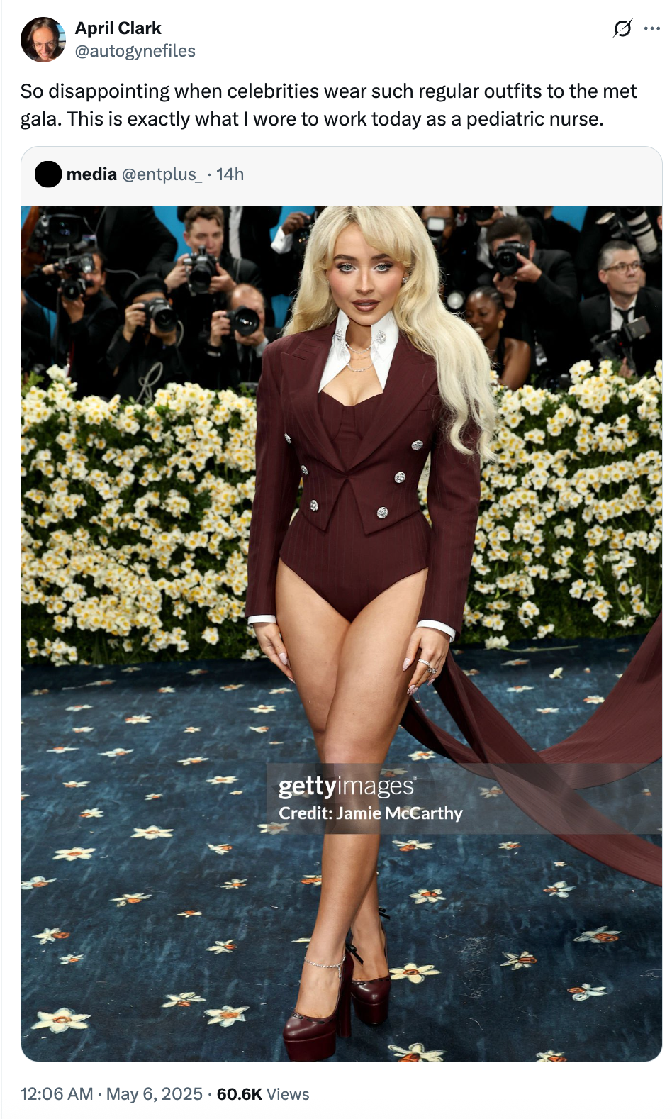 Person in a tailored blazer with structured shoulders and high-cut bottom on a floral backdrop, reminiscent of a red carpet event