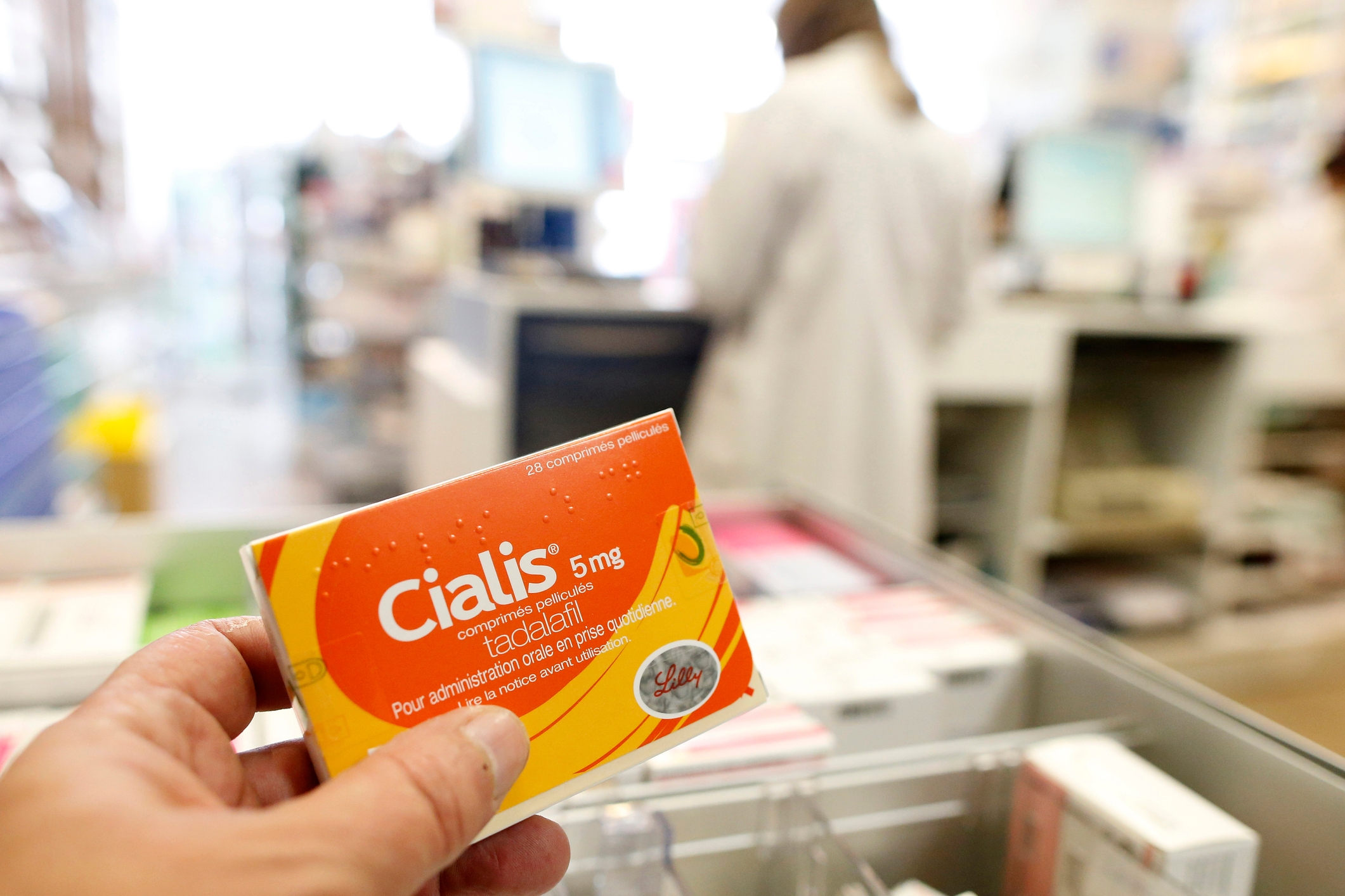 Person holding a Cialis 5mg box in a pharmacy, focusing on erectile dysfunction medication