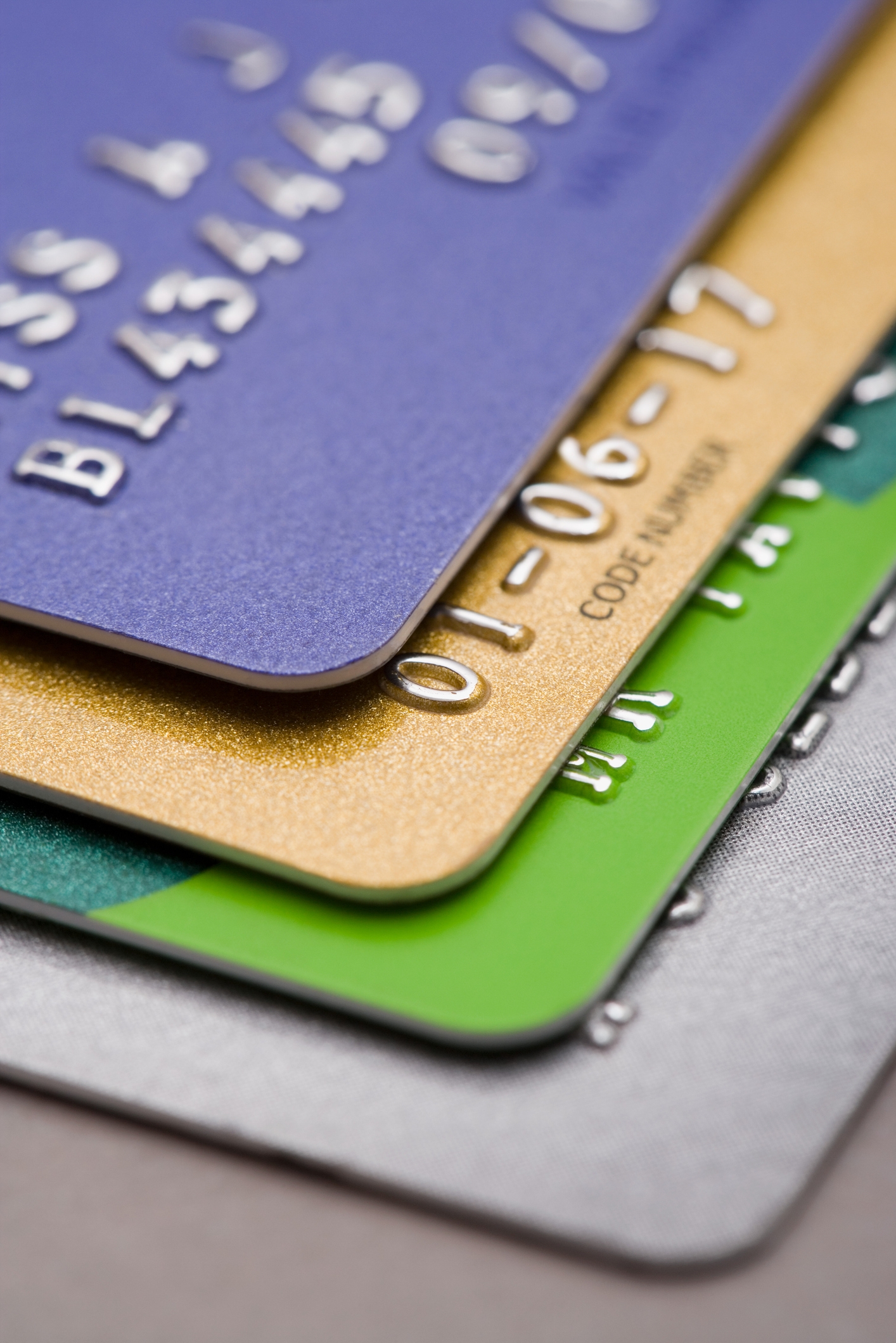 Stack of credit cards with embossed numbers and different textures, focusing on financial details