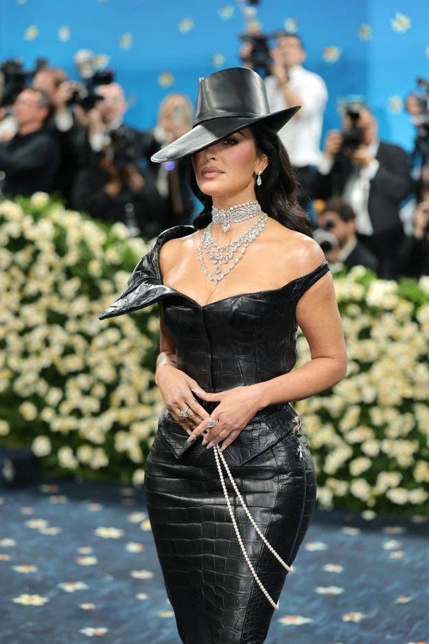 Kim Kardashian in a fitted black textured gown with a wide-brimmed hat at the Met Gala
