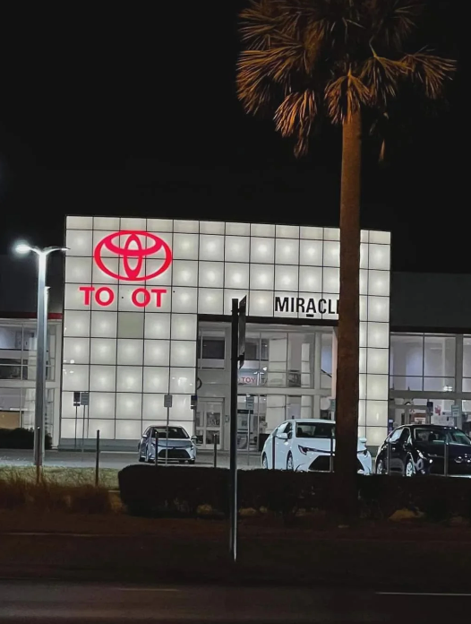 Toyota dealership at night; some of the Toyota sign is missing, so it appears to read "toot"