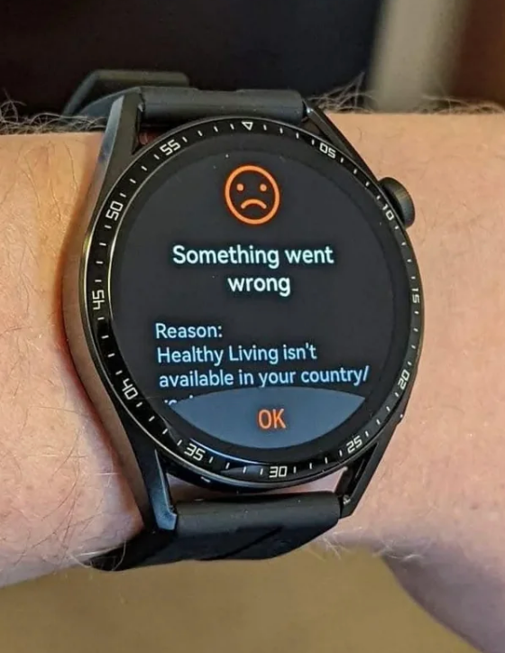 Smartwatch display shows an error message: "Something went wrong. Reason: Healthy Living isn't available in your country"