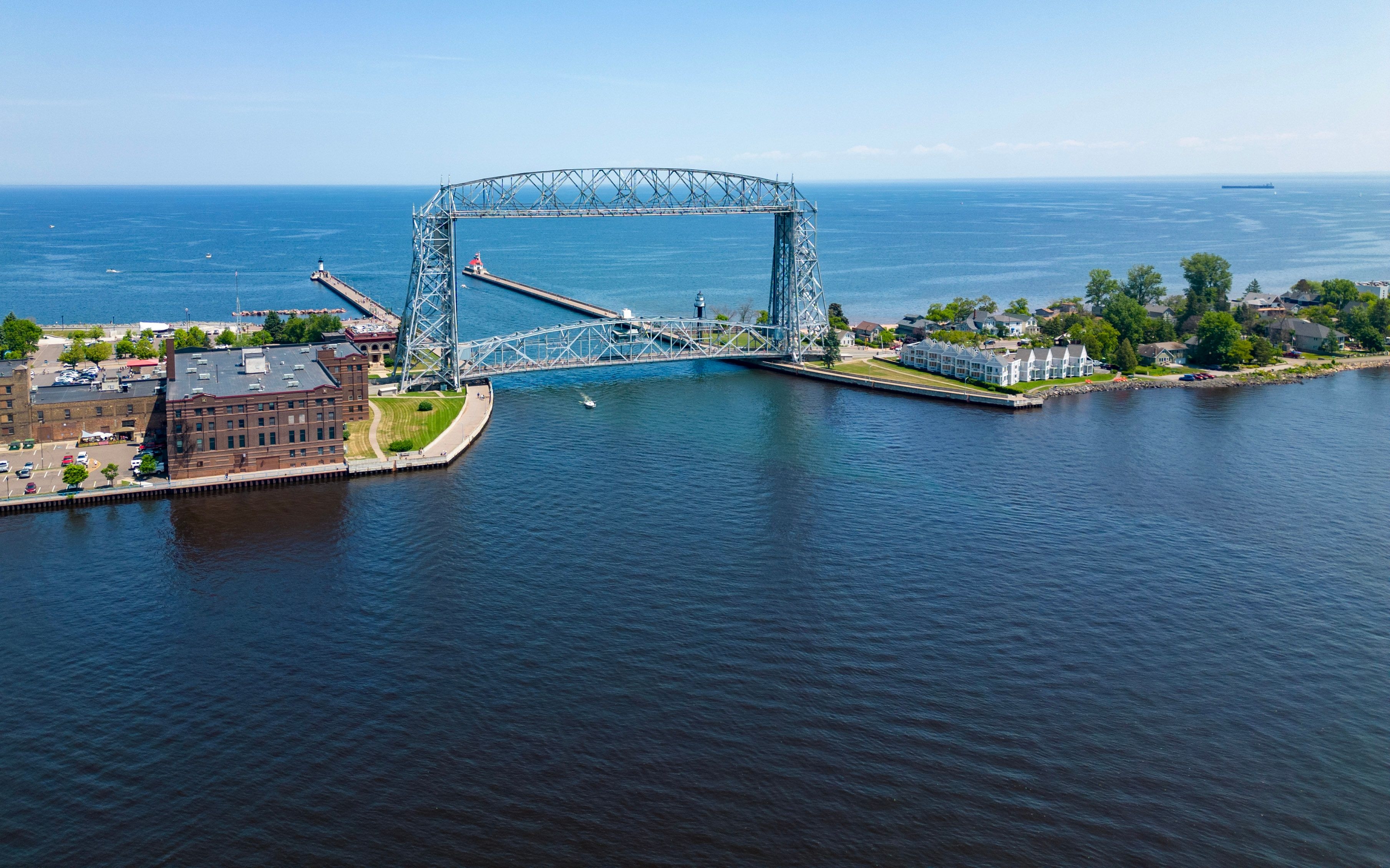 Aerial view of a large lift bridge over a body of water, connecting areas with buildings and greenery on both sides