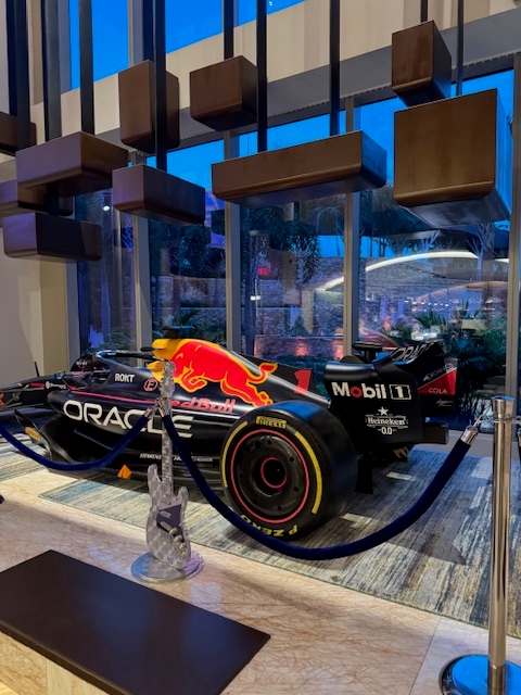 Formula 1 race car displayed indoors with large windows and modern decor in the background, adding a touch of elegance to the travel-themed setting