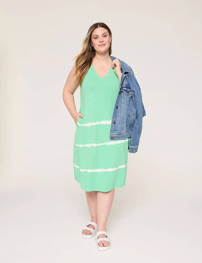 Person wearing a casual sleeveless greenish  formal  with achromatic  stripes and a denim overgarment   implicit    1  shoulder, paired with achromatic  sandals