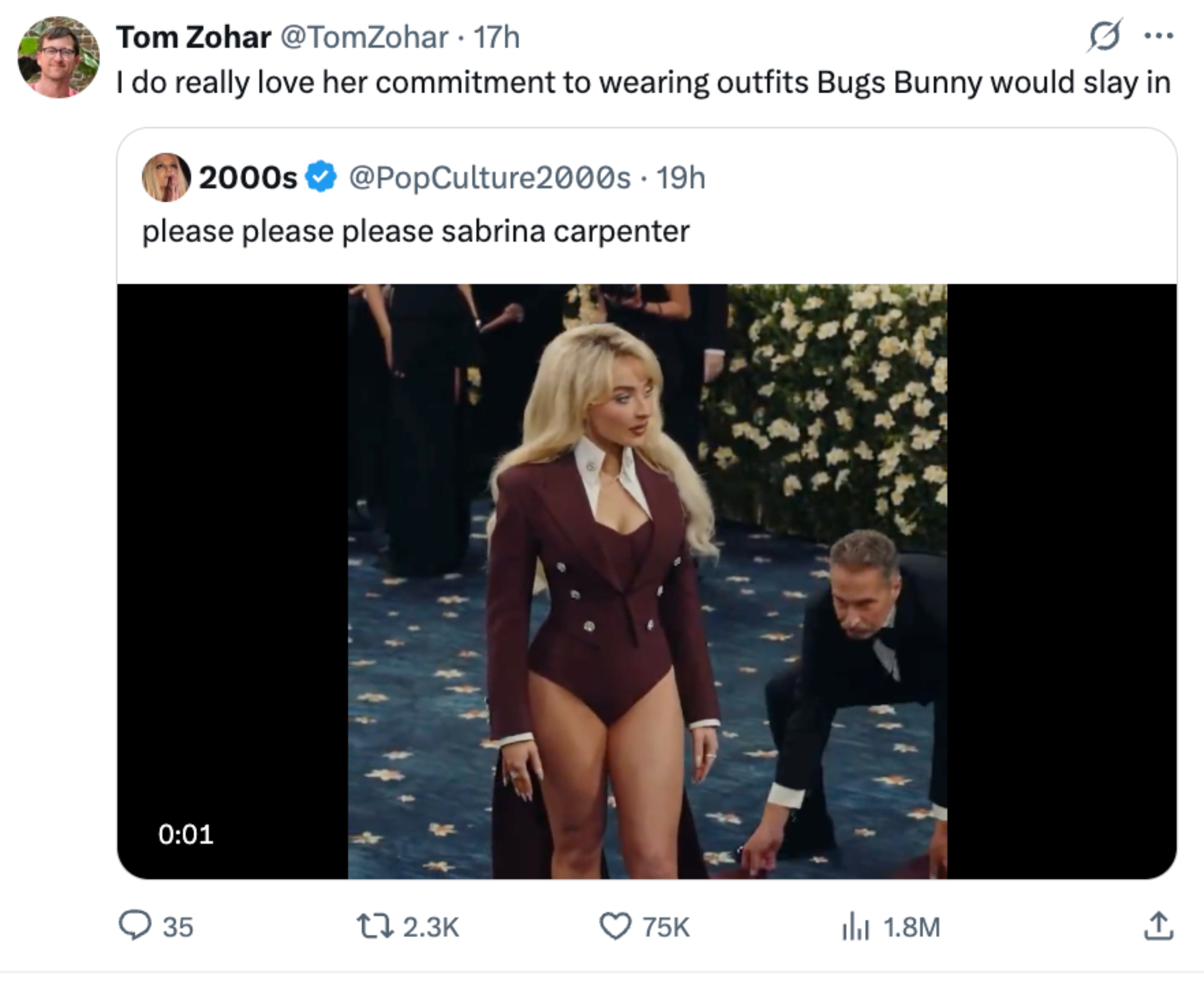 A performer in a stylish blazer-style bodysuit on a blue and white carpet, attended to by an assistant