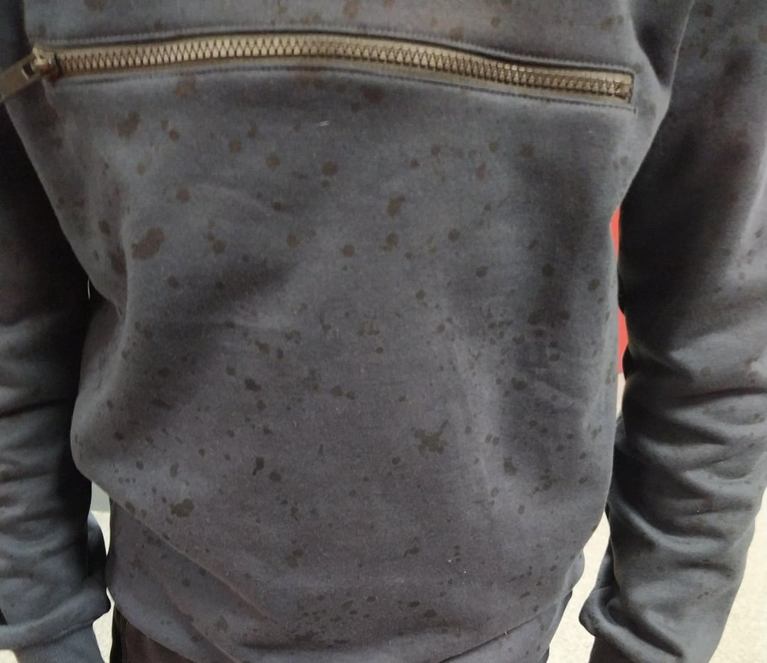 A sweatshirt with a front zipper pocket shows spots suggesting wetness or slight staining
