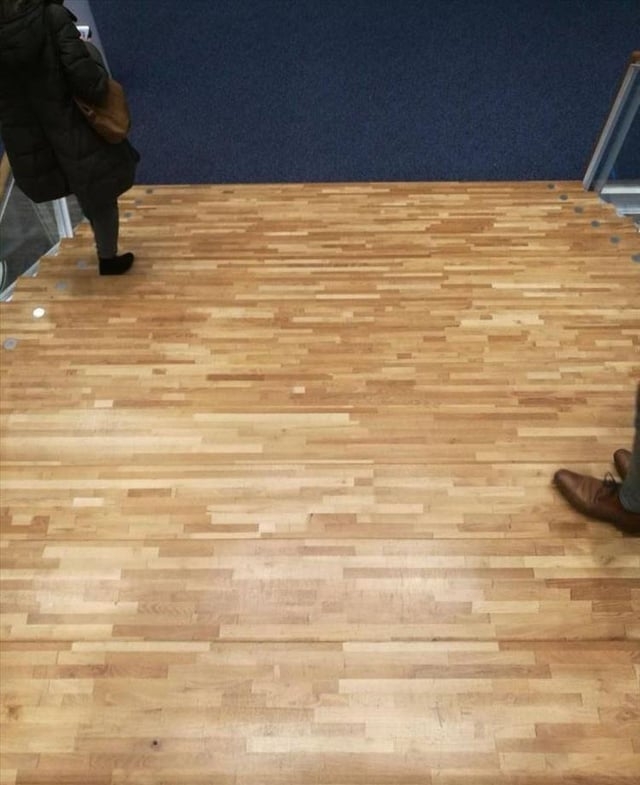 Optical illusion of a wooden floor resembling stairs, with a person walking on it, creating a sense of descending steps