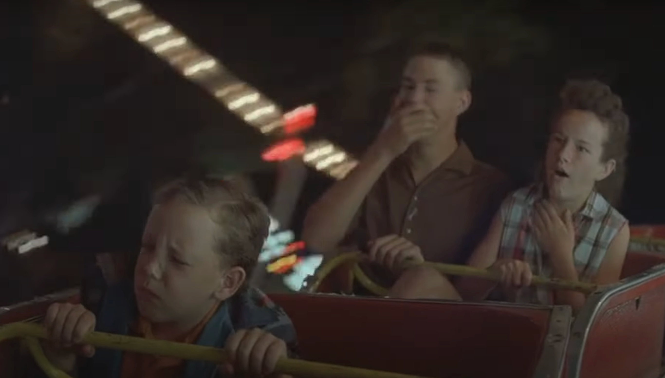 three kids on a canrival ride, appearing nauseous